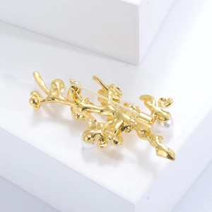 Close-up of golden coral branch brooch back with pearl details and secure pin clasp