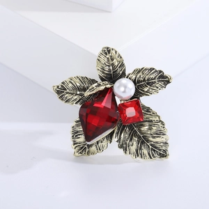 Detail of vintage flower brooch with red gemstones and pearl on golden petals