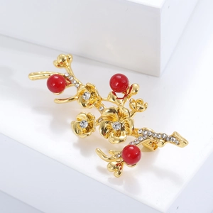 Detailed close-up of a vintage golden flower branch brooch with red pearls and zircons