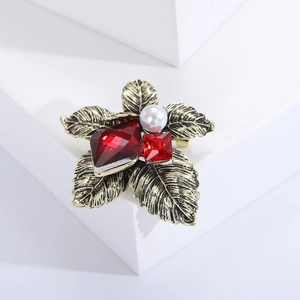 Macro view of vintage bronze flower brooch with red faceted gemstones and white pearl
