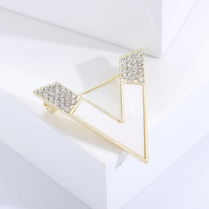 Close-up of golden V-shaped brooch with mother-of-pearl inlay and sparkling rhinestones
