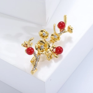 Close-up of golden plum blossom brooch with red pearls and sparkling crystals