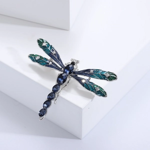 Detail of dragonfly brooch featuring blue enamel wings and inlaid white crystals