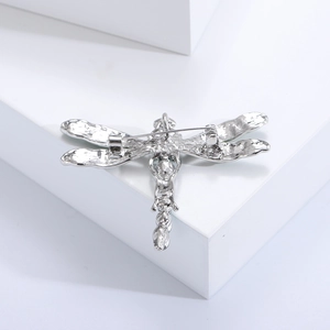 Macro detail of silver dragonfly brooch back showing safety pin and metal texture