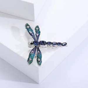 Detailed close-up of dragonfly brooch with blue-green enamel wings and crystal inlay