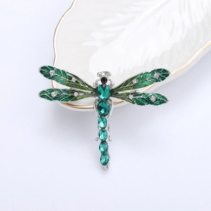 Macro detail of enamel dragonfly brooch with green gemstones and sparkling rhinestones