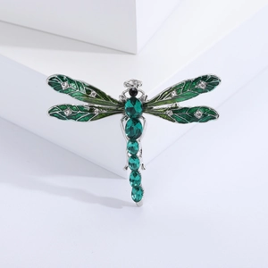 Detail of dragonfly brooch with green enamel wings and sparkling rhinestones on silver base