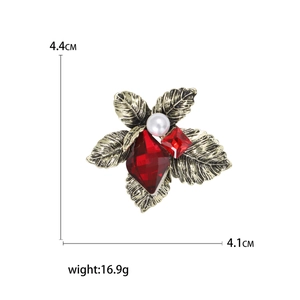 Vintage gold leaf brooch with white pearl and red faceted crystals on white background