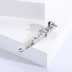 Macro shot of vintage silver rose brooch on white geometric blocks featuring safety pin