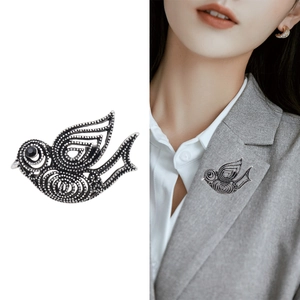Broche vintage en forme d'oiseau argenté ajouré avec œil en pierre noire sur chemise