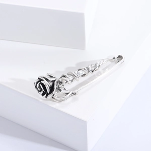 Detailed close-up of a vintage silver rose brooch on a clean white geometric background