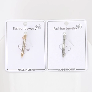 Macro detail of gold and silver pencil brooches with pearls and rhinestones on display card