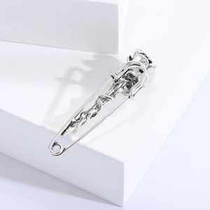 Close-up of vintage silver rose vine brooch with gothic design on a white pedestal