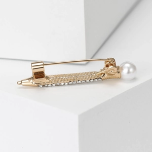 Vintage gold alloy pen brooch with white pearls and rhinestones on a white display block