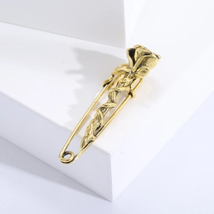 Macro detail of a vintage golden rose brooch pin on a minimalist white platform