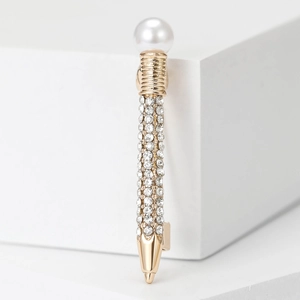 Detailed close-up of pencil-shaped brooch with pearls and rhinestones on gold alloy