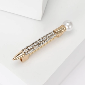 Macro shot of creative gold pen brooch with white rhinestones and a white pearl accent