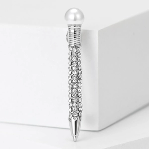 Macro detail of silver pen brooch with sparkling rhinestones and a white pearl