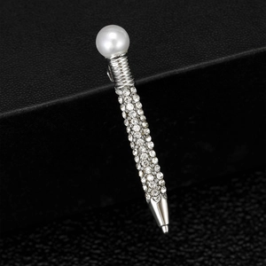 Macro shot of silver-tone pen-shaped brooch with white pearl and pave-set rhinestones