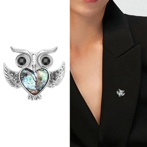 Detailed owl brooch with abalone shell heart and black rhinestones on a blazer
