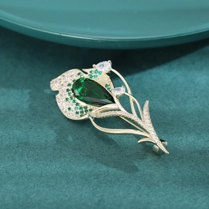 Vue macro d'une broche tulipe avec pierre verte en poire et incrustation de zircons