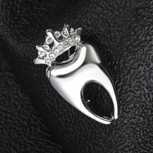 Vue rapprochée d'une broche dent en argent avec couronne strass sur cuir noir