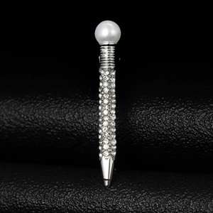Macro shot of silver alloy pen brooch with pearl top and pavé rhinestones on black leather