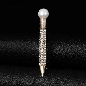 Macro shot of gold-plated pen brooch featuring rows of crystal rhinestones and a white pearl