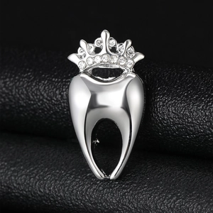 Vue macro d'une broche dentaire argentée avec couronne en strass sur cuir texturé noir