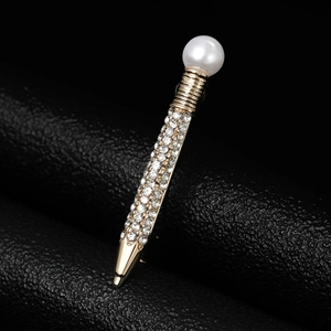 Detail of a gold pen-shaped brooch with a white pearl and sparkling crystals on black leather