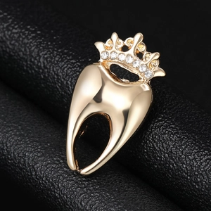 Détail macro d'une broche dent couronne dorée avec strass brillants sur cuir noir