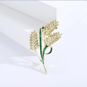 Dettaglio spilla a forma di spiga dorata con cristalli gialli e smalto verde