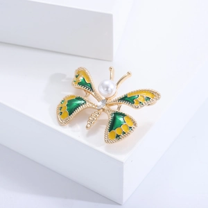 Vue détaillée de la broche papillon en émail vert et jaune avec perle d'imitation