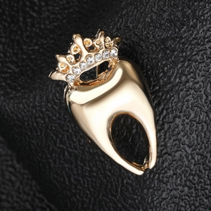 Gros plan d'une broche couronne dentaire dorée avec strass sur cuir noir élégant
