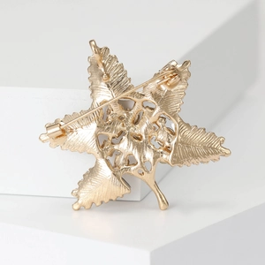 Back view of baroque gold maple leaf brooch with detailed veins on white geometric stand