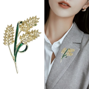 Elegante spilla a spiga di grano dorata con cristalli gialli e smalto verde su giacca