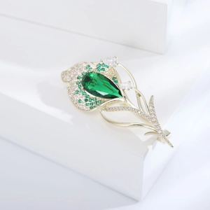 Détail d'une broche en forme de feuille de tulipe dorée avec zircons verts et blancs