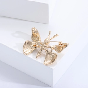 Vue arrière détaillée d'une broche papillon dorée montrant le fermoir de sécurité en métal