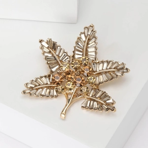 Macro shot of gold leaf brooch with clear baguette crystals and amber rhinestones