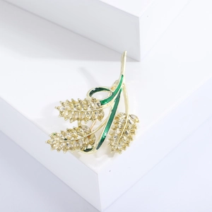 Elegante spilla a spiga dorata con cristalli gialli e smalto verde su base bianca