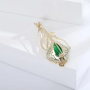 Vue macro d'une broche tulipe dorée avec zircon vert et détails fins en diamants
