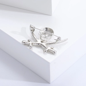 Silver metal skull and crossbones brooch showing the back pin mechanism and texture