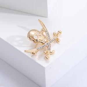 Detailed close-up of a gold pirate skull and crossed swords brooch with sparkling rhinestones