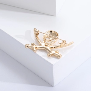 Macro detail of the golden alloy skull brooch showing the secure safety pin clasp on back