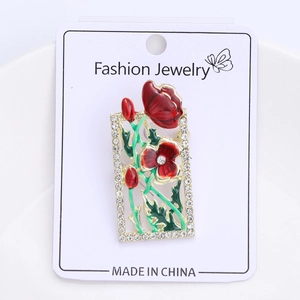 Macro detail of enamel floral brooch with red flowers and sparkling crystal border