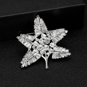 Macro detail of baroque silver brooch featuring clear leaf-shaped rhinestones on black background