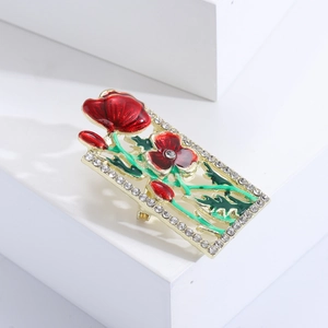 Macro shot of rectangular gold flower brooch with red enamel petals and diamond accents