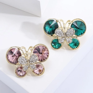 Détail de broches papillon avec cristaux émeraude et violets sur monture dorée