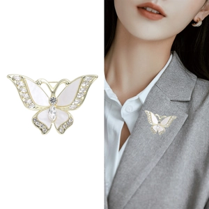 Elegante broche de mariposa dorada con nácar y cristales brillantes sobre una chaqueta