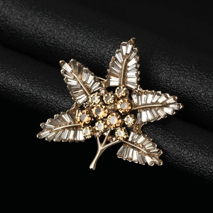 Macro shot of gold leaf brooch with baguette rhinestones on black leather texture